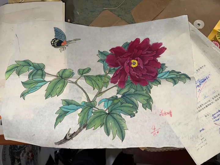 A painting of flowers and a butterfly laid on a table.