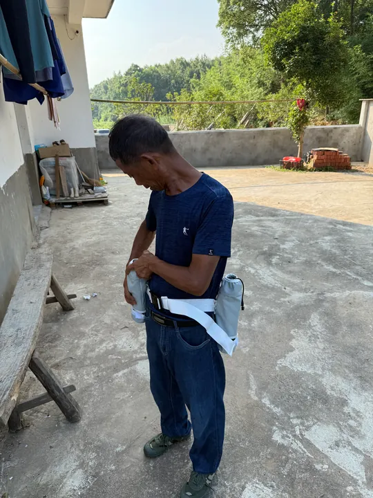 A man adjusting white straps around his waist in a courtyard.
