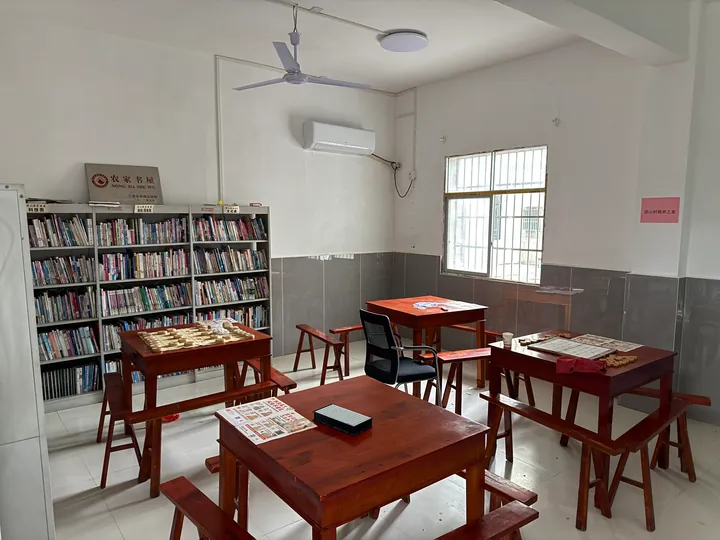 Bookshelves, chess tables, and leaflets in a village reading room.
