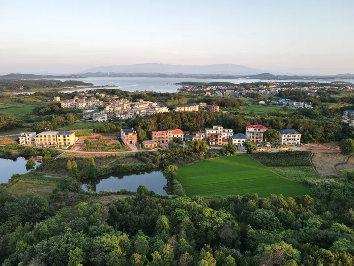 An aerial view of a village, fields, and water in the distance.