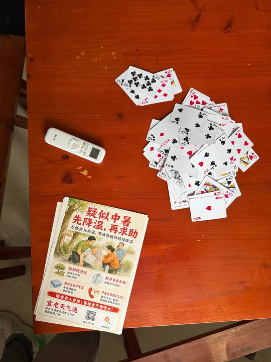 An overhead view of playing cards and YiLao WeatherLink heat-safety leaflets.