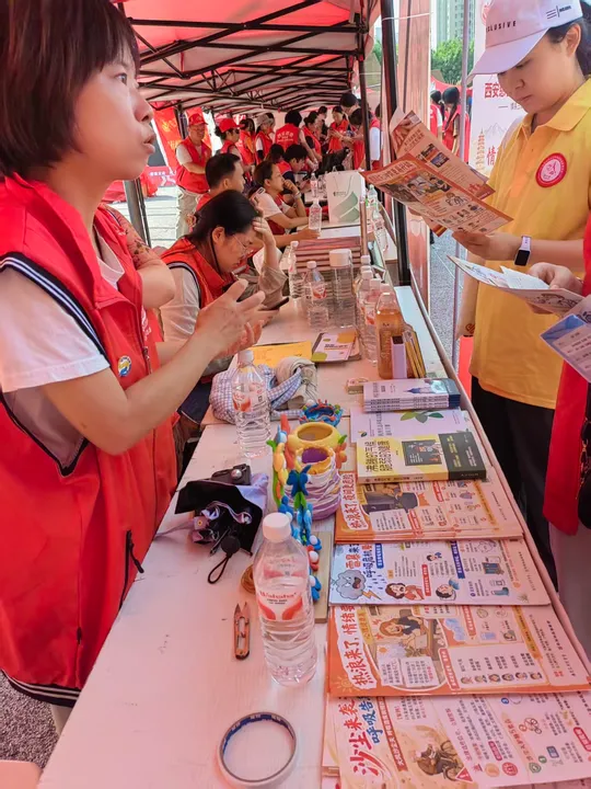People discussing printed climate and health materials under a red tent.