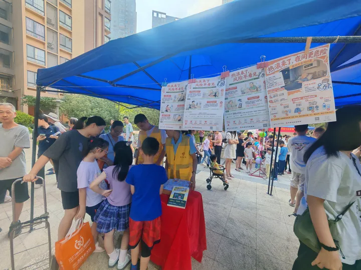Adults and children gathered around health posters and a table under a blue tent.