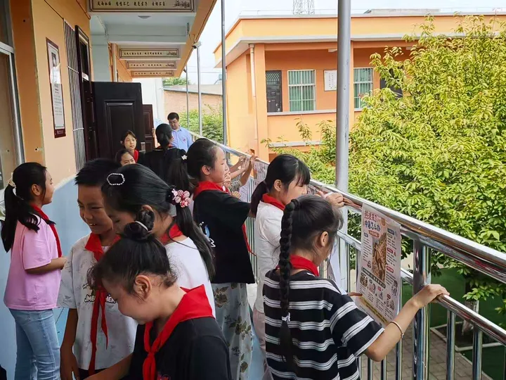 Children reading climate and health posters displayed along a corridor railing.