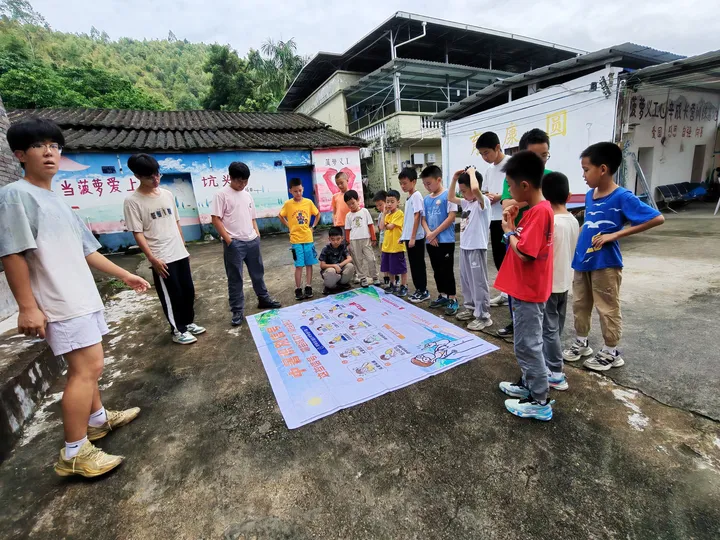 青少年在院落围绕铺放的大型“中暑识别信号”海报互动。