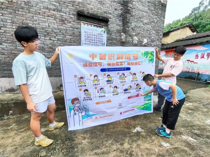 A child pointing to a heat-warning poster held up by two participants.