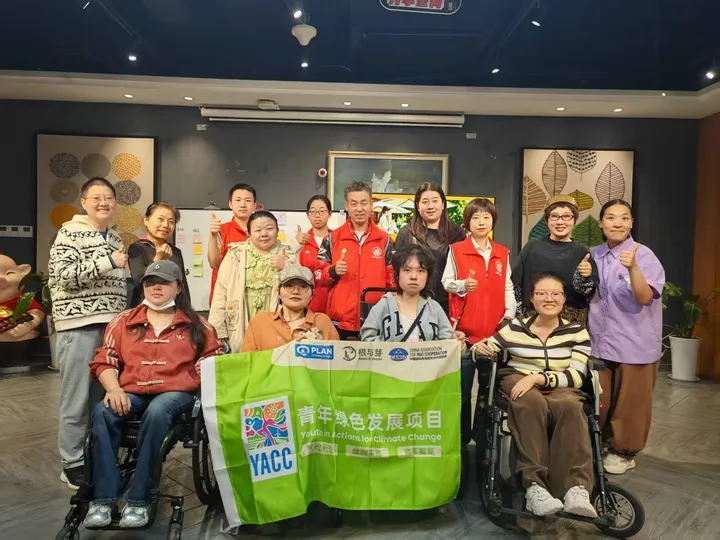 室内多人合影，前排有轮椅使用者；合影横幅写“青年绿色发展项目”“YACC”。