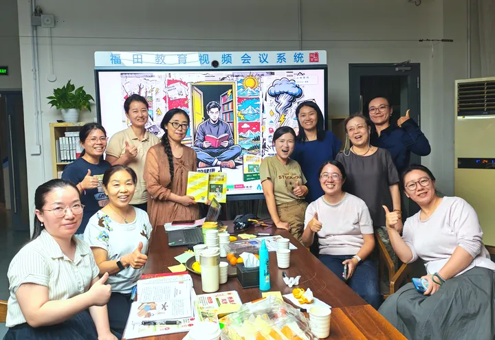 A group photograph in a meeting room with books and materials on the table.