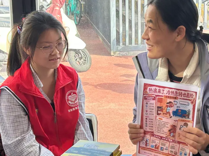 Two people talking while one holds a leaflet about heat and sudden temperature changes.