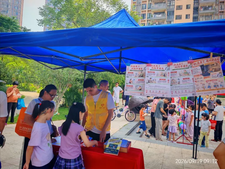 Adults and children interacting with posters and materials under a blue tent.