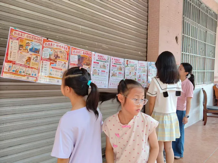 Children viewing a row of climate and health posters in front of a roller shutter.